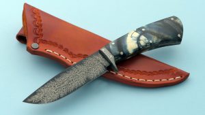Dan Lewis, ABS Journeyman Smith, created this Frame Handle knife with Feather Pattern Damascus and exquisite Cross Cut Mastodon Ivory handle. Comes with custom leather sheath.